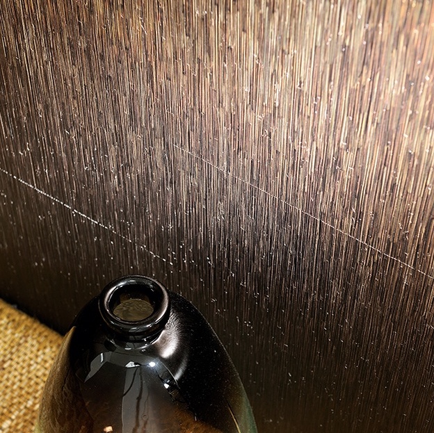 Glinsterend metallic Elitis Formentera Alegria VP 719 01 behang met verticale structuur, naast een donkere glanzende vaas.