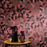 Roze en zwarte geometrische Elitis Formentera Juego de Paja VP 717 06-behang met twee sierkannen op een gele ronde tafel.