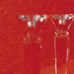 Twee glazen objecten voor een felrode Elitis Glass Nacres VP 640-16 wandbekleding met een glanzende textuur.