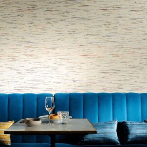 Moderne zithoek met blauwe fluwelen bank en Elitis Indiana-1 behang met subtiele kleurrijke strepen.