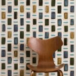 Houten designstoel voor een Elitis Initiation Ornements TP313 behang met kleurrijk geometrisch patroon.