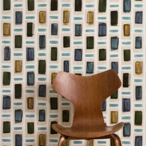 Houten designstoel voor een Elitis Initiation Ornements TP313 behang met kleurrijk geometrisch patroon.