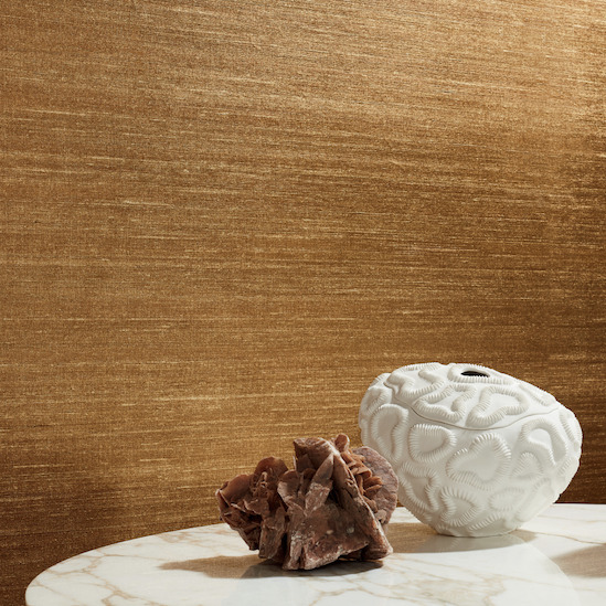 Witte vaas en rozenkwartsdecoratie op een marmeren tafel voor een goudkleurige Elitis Kosa Silk Metal VP 935 91 wandbekleding.