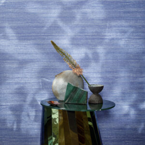 Stilleven met decoratieve objecten op een glanzende tafel voor een blauwe Elitis Kosa Silk Metal VP 935 95 wandbekleding.