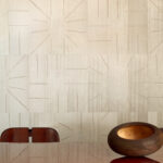 Beige Elitis Le Roi Soleil behang met geometrisch zonnestraalpatroon in een modern ingerichte eetkamer.