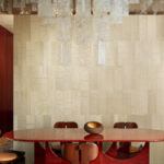 Moderne eetkamer met Elitis Le Roi Soleil RM 1038 03 Marqueteries behang, glanzende hanglamp en houten meubelen.