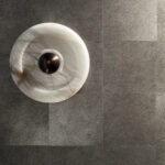 Detail van Elitis Movida VP 948 90 metaalbehang met een ronde wanddecoratie in marmerlook.