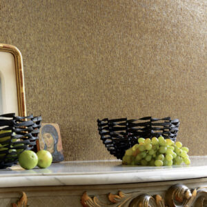Sfeervolle interieursetting met Elitis Nacres VP 640 24 goudkleurig behang, zwarte manden en fruit op een sierlijke marmeren schouw.