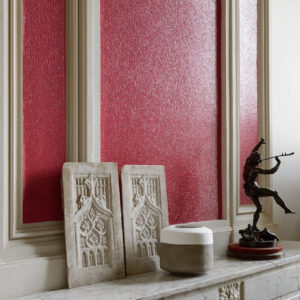 Wandbekleding Elitis Nacres VP 640 30 in felrood met glinstereffect, gecombineerd met klassiek beeldhouwwerk en een bronzen standbeeld op een marmeren schouw.