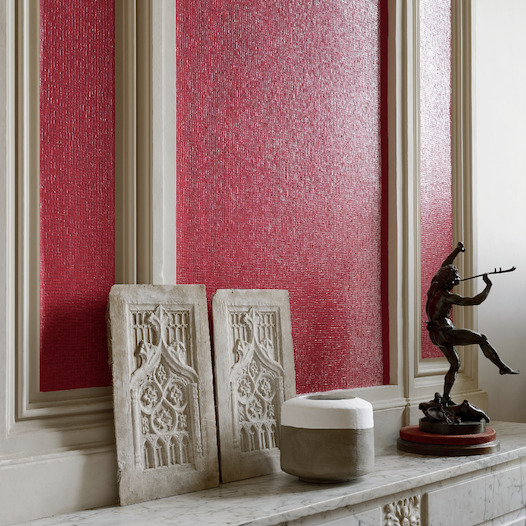 Wandbekleding Elitis Nacres VP 640 30 in felrood met glinstereffect, gecombineerd met klassiek beeldhouwwerk en een bronzen standbeeld op een marmeren schouw.