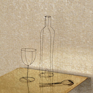 Draadsculpturen van een fles, glas en lepel op een gouden tafel voor een Elitis Nacres VP 940 23 muur.