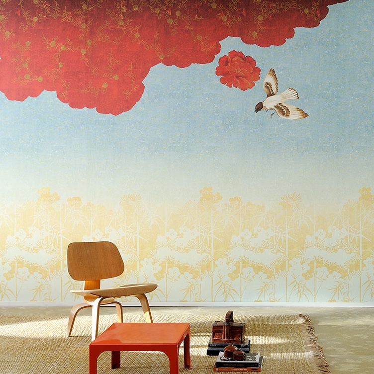Moderne interieursetting met een Elitis Nouvelles Orientales-muur met rode bloemen, een vliegende vogel en een houten stoel op een geweven tapijt.