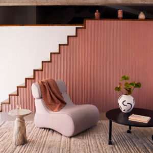 Moderne woonkamer met Elitis Pilastre RM 1043 51 Rayures Jumelles behang in roze tinten en een designfauteuil.
