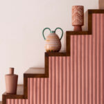 Trap bekleed met roze Elitis Pilastre RM 1043 51 Rayures Jumelles behang, versierd met keramische vazen en een lamp.