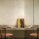 Moderne interieursetting met Elitis Sangpi VP 1018 06 behang, een marmeren wandplank, twee houten stoelen en abstract schilderij tegen de muur.