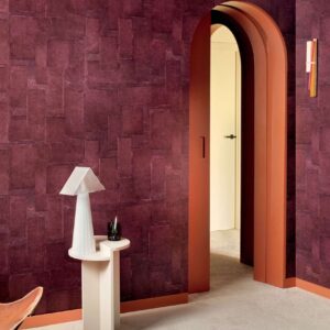 Moderne interieurhoek met Elitis Sangpi VP 1018-39 behang in dieprode tint, een boogdeur en een designlamp op een wit tafeltje.