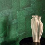Beige designvaas op zwarte tafel voor groen Elitis Sangpi VP 1018 60 behang met textuur en patroon.