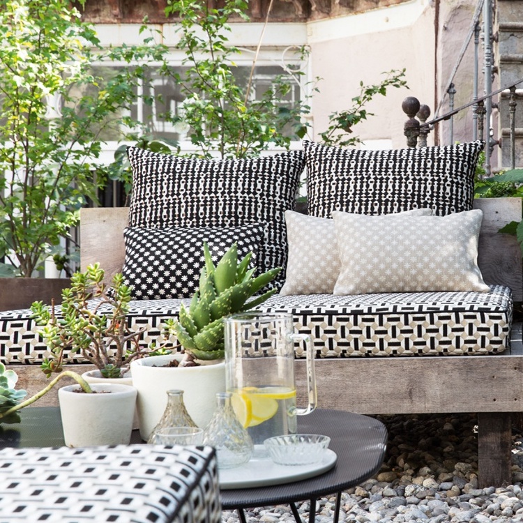 Stijlvol ingerichte tuinlounge met Elitis Sebino outdoor kussens in zwart-witte geometrische patronen.