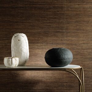 Decoratieve objecten op een tafel voor een luxe Elitis Talamone Seta wandbekleding in warme bruintinten.