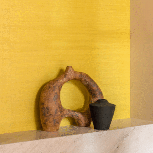 Decoratieve vazen op een marmeren schouw tegen een gele Elitis Tribus sisal muur.