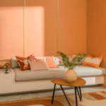Moderne woonkamer met Elitis Tribus sisal muurafwerking in warme perzikkleur, een lichtgrijze bank met sierkussens en een houten salontafel met vaas.