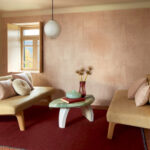 Sfeervolle woonkamer met Elitis Atelier d'artiste VP 880 53 behang, beige zitmeubels en een ovale salontafel.