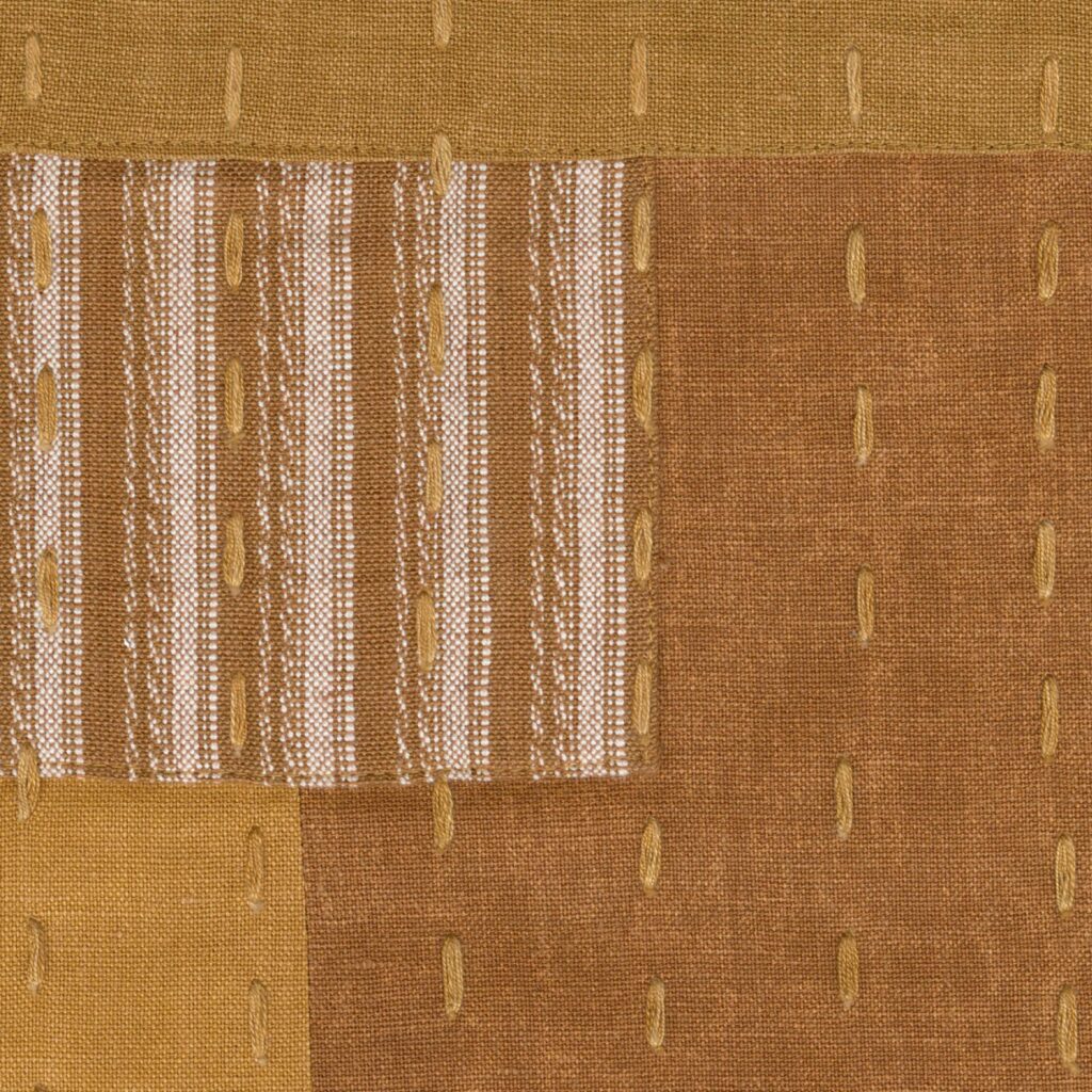 Textielpatroon uit de Elitis Baleares Costa collectie met bruine en okergele vlakken, versierd met verticale stiksels en strepen.