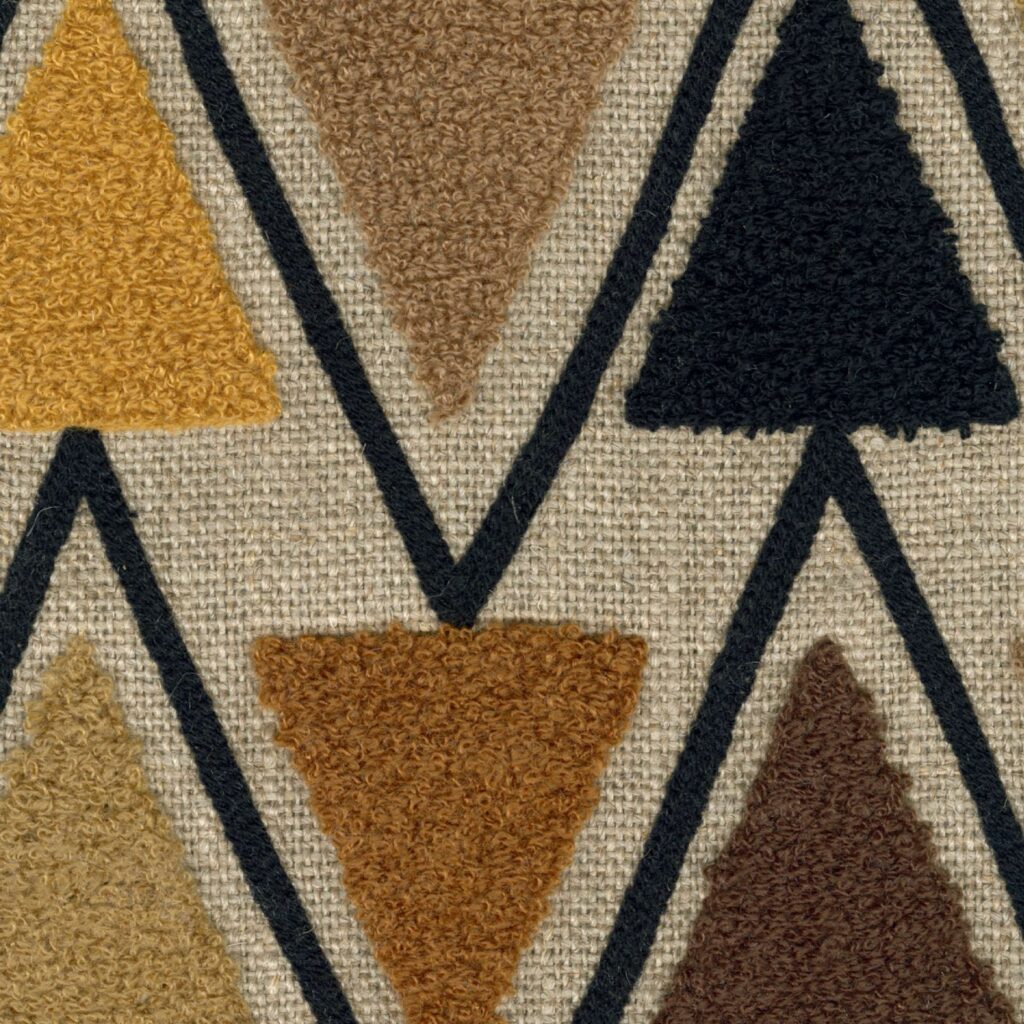 Detail van Elitis Baleares Joya LZ 904 79 stof met kleurrijke getufte driehoeken op een geweven achtergrond.