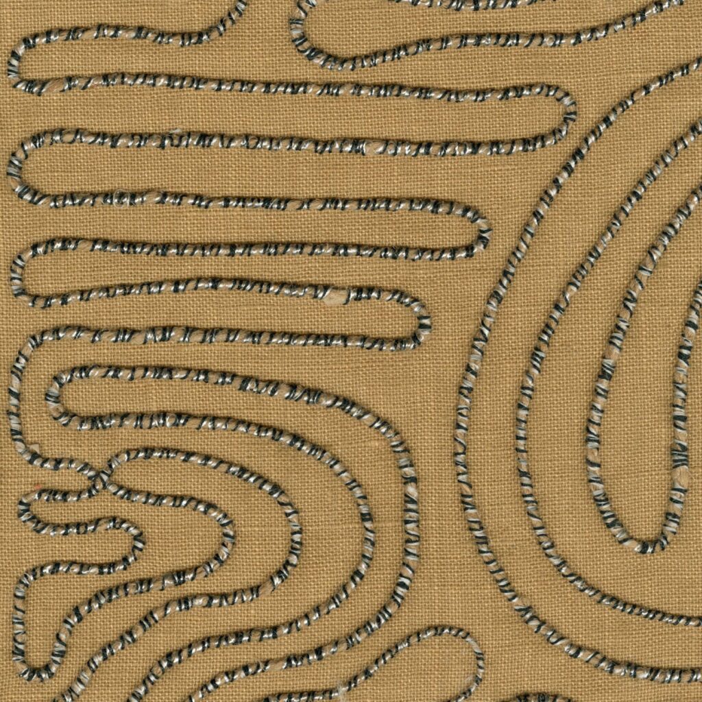 Decoratieve stof uit de Elitis Baleares Llenya LZ 905 29 collectie met een golvend, geborduurd patroon op een bruine achtergrond.