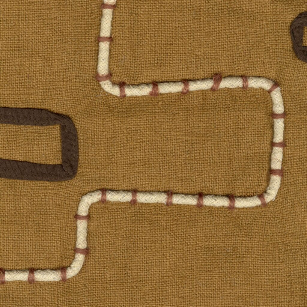 Detail van Elitis Baleares Pacha LZ 901 29 textiel met een bruin linnen achtergrond en opgestikte witte en bruine geometrische lijnen.