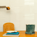 Woonkamer met Elitis Art Paper Okinawa behang, houten tafel, designlamp en decoratieve accessoires.