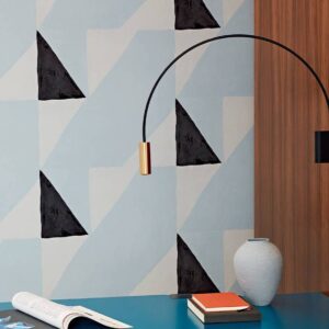 Moderne interieurhoek met Elitis-behang uit de Voile de papier-collectie met abstract zwart-wit patroon, blauwe tafel, vaas en designlamp.