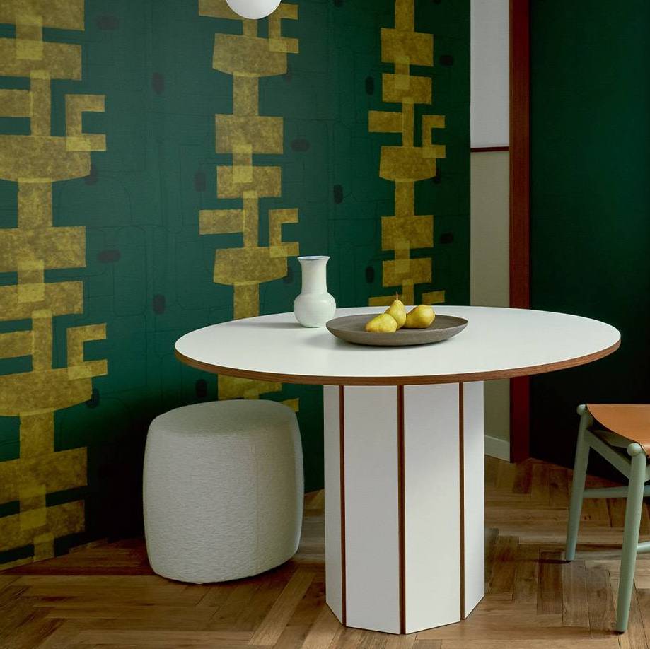 Moderne eethoek met een ronde witte tafel en Elitis-behang Cuzco TP 332 uit de Voile de Papier collectie op de achtergrond.