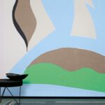 Abstract Elitis-behang uit de Cyclades-collectie met kleurrijke organische vormen in groen, blauw, bruin en zwart.