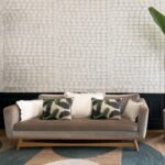 Bank met sierkussens voor een muur met Elitis-behang Ecrin Puerto Princesa in een licht patroon.