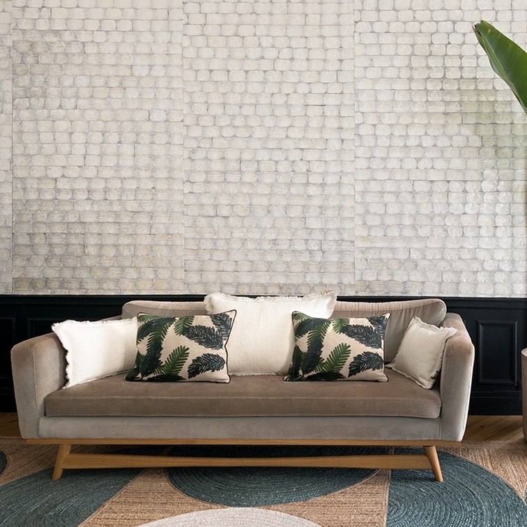 Bank met sierkussens voor een muur met Elitis-behang Ecrin Puerto Princesa in een licht patroon.