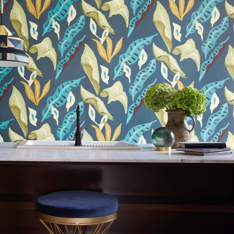 Interieur met Elitis-behang "Fleur de Lune" met kleurrijk bladmotief achter een marmeren wastafel en decoratieve accessoires.
