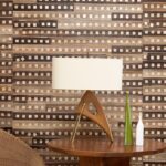 Houten tafellamp en decoratieve vazen voor een wand met Elitis-behang Iloilo in aardetinten en geometrisch patroon.