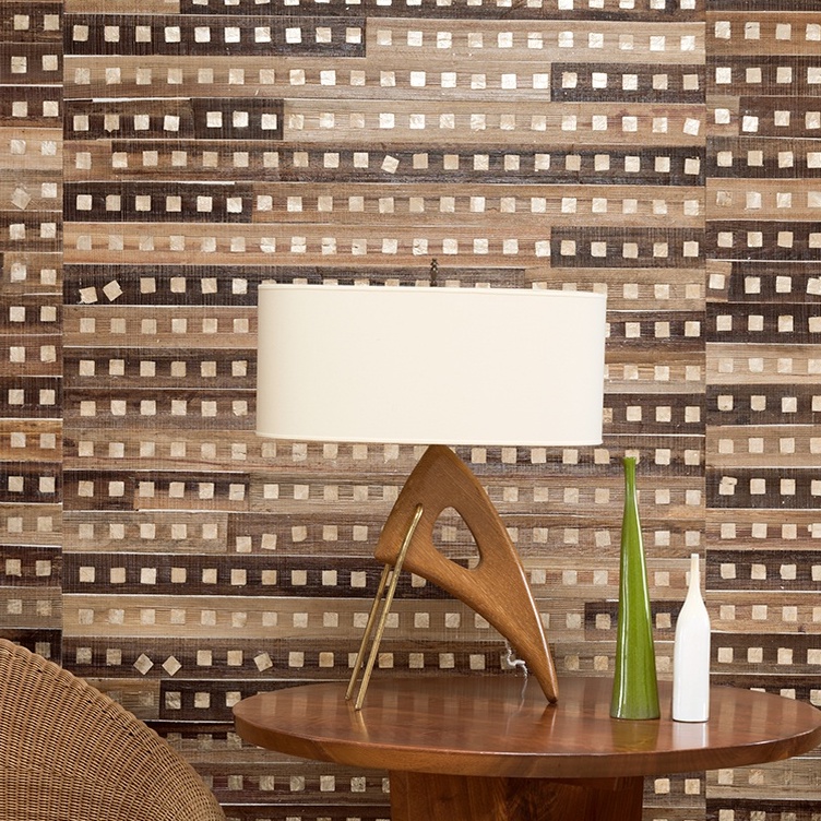 Houten tafellamp en decoratieve vazen voor een wand met Elitis-behang Iloilo in aardetinten en geometrisch patroon.