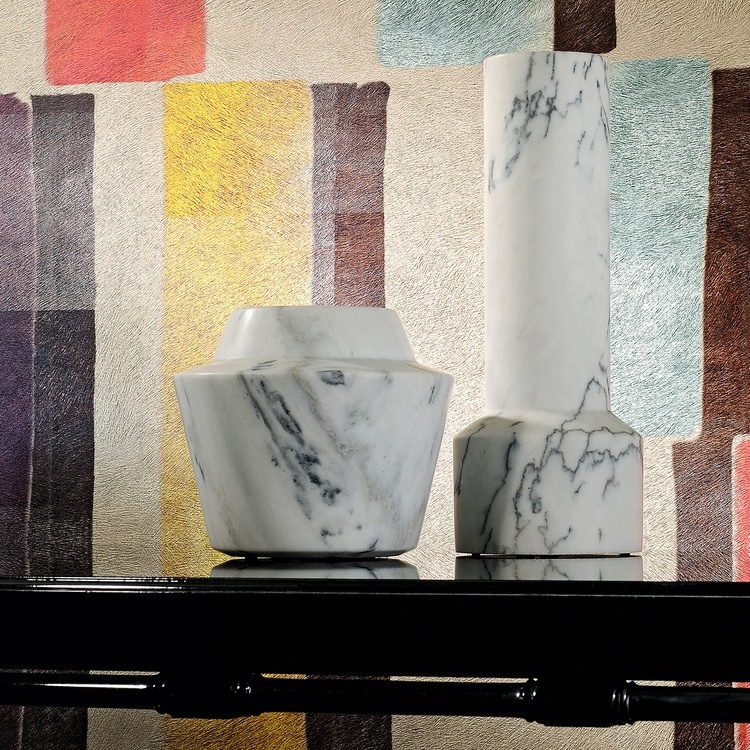 Twee marmeren designvazen op een zwarte tafel voor een kleurrijk Elitis Indomptee Tribeca VP 617 01 behang.