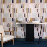 Interieur met Elitis-behang Initiation Renaissance in abstract patroon, voorzien van een designstoel en moderne console.