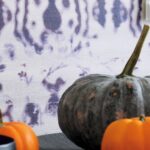 Grijze en oranje pompoenen op een tafel met Elitis Kandy Brit Pop behang op de achtergrond.