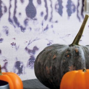 Grijze en oranje pompoenen op een tafel met Elitis Kandy Brit Pop behang op de achtergrond.