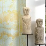 Twee stenen sculpturen voor Elitis-behang uit de La Montagne Sacrée-collectie met een gele en lichtblauwe botanische print.