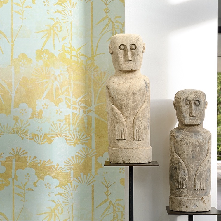Twee stenen sculpturen voor Elitis-behang uit de La Montagne Sacrée-collectie met een gele en lichtblauwe botanische print.