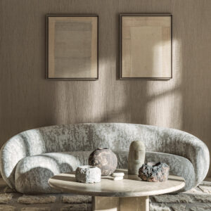 Stijlvolle woonkamer met Elitis Lin Plâtre Innocent behang, afgeronde bank en kunstzinnig decor op een ronde salontafel.