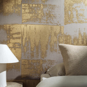 Slaapkamer met Elitis behang Lin Plâtre Muse RM 1047 92 in goud- en grijstinten, naast een bed en witte lamp.