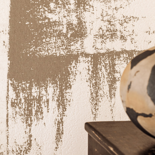 Close-up van Elitis behang Lin Plâtre Toile d'artiste met een abstract, verweerd patroon in beige en wit naast een houten meubel en decoratief object.