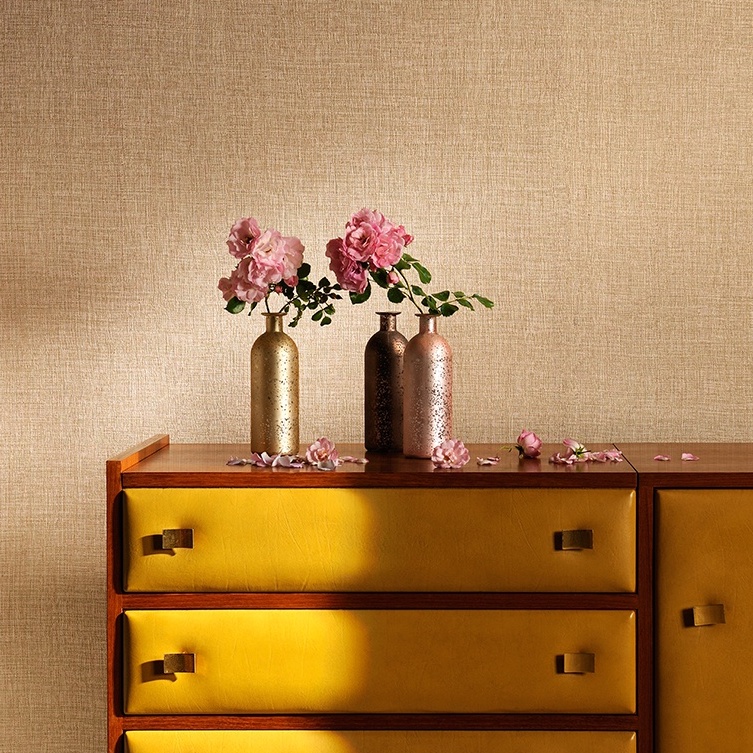 Kast met gele lades voor Elitis Madagascar-behang, versierd met bloemen in metallic vazen.