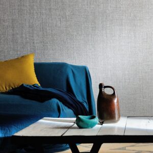 Zithoek met blauw gedrapeerde bank, okergeel kussen en Elitis behang Madagascar op de achtergrond.